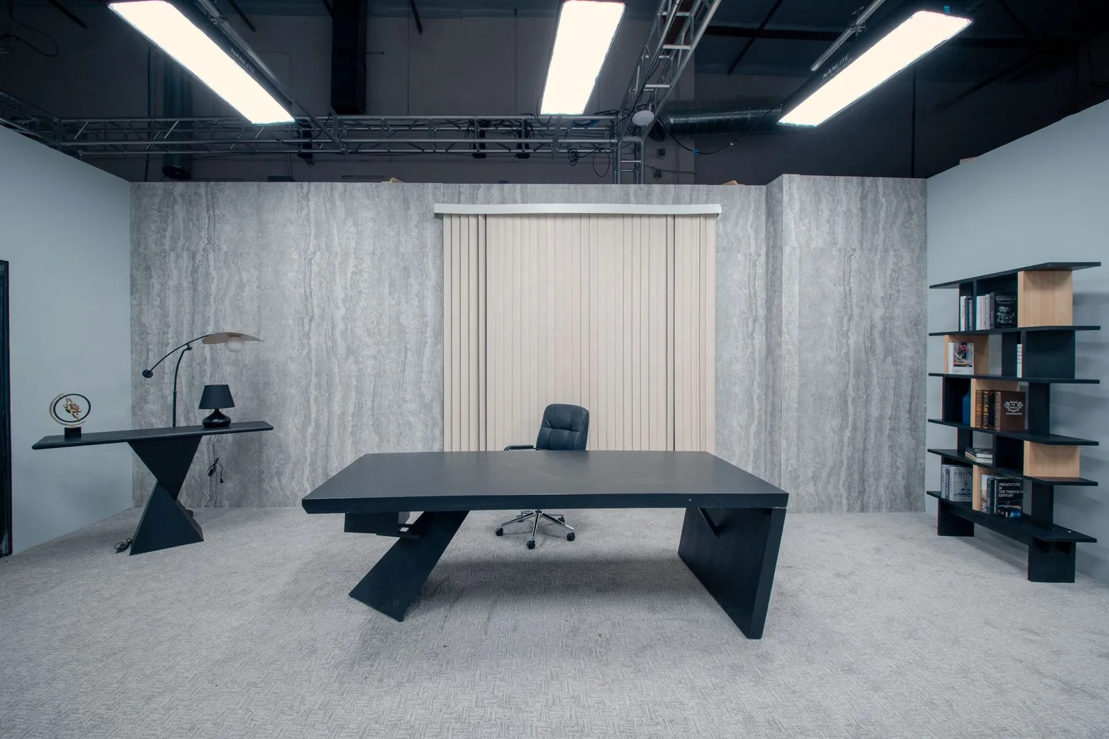 Private office: black desk centred against travertine walls and blinds