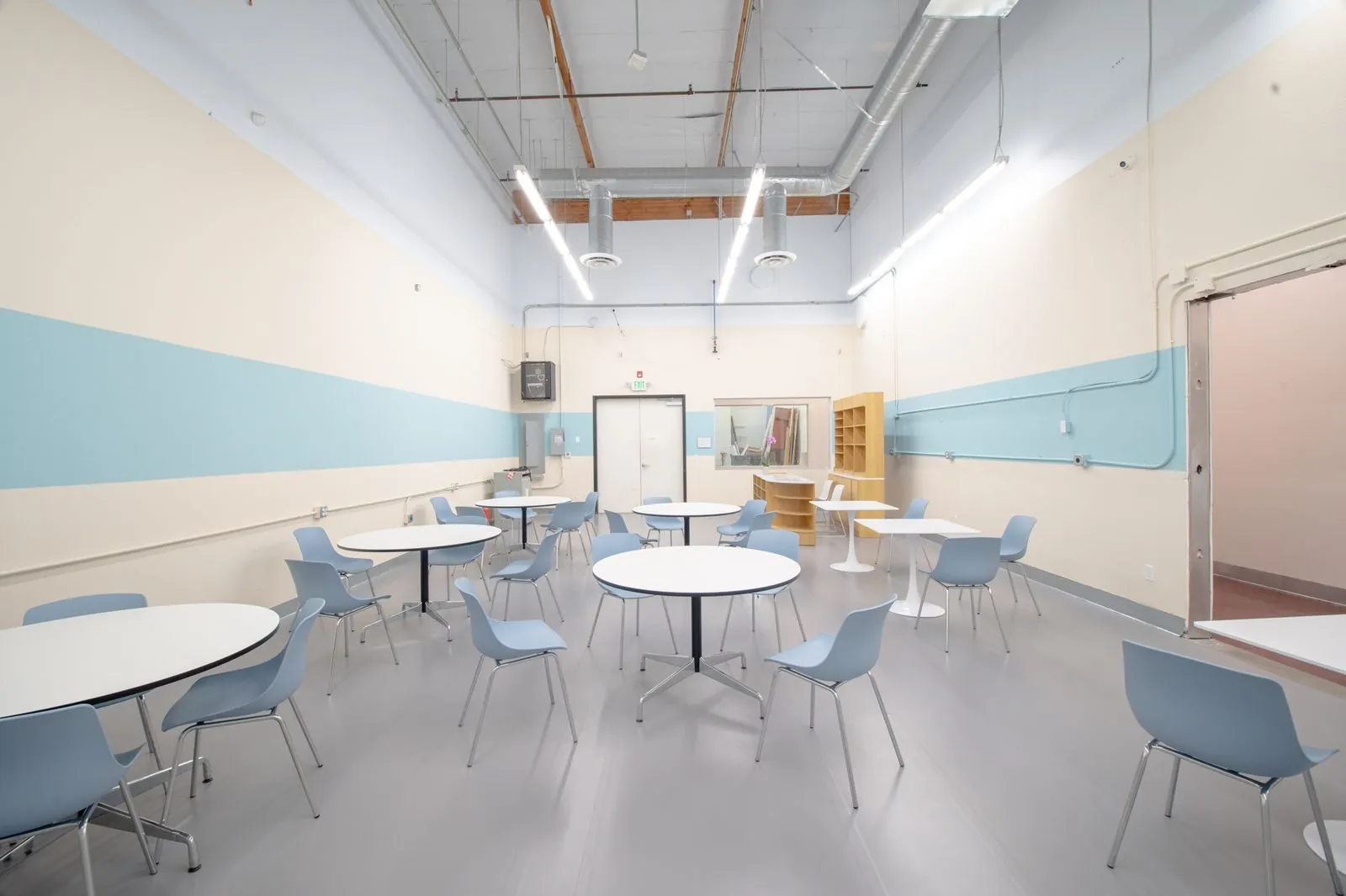 Cafeteria tables and chairs against the striped wall