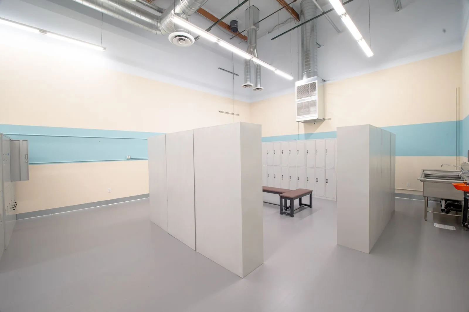 Locker room with changing partitions and a wash trough