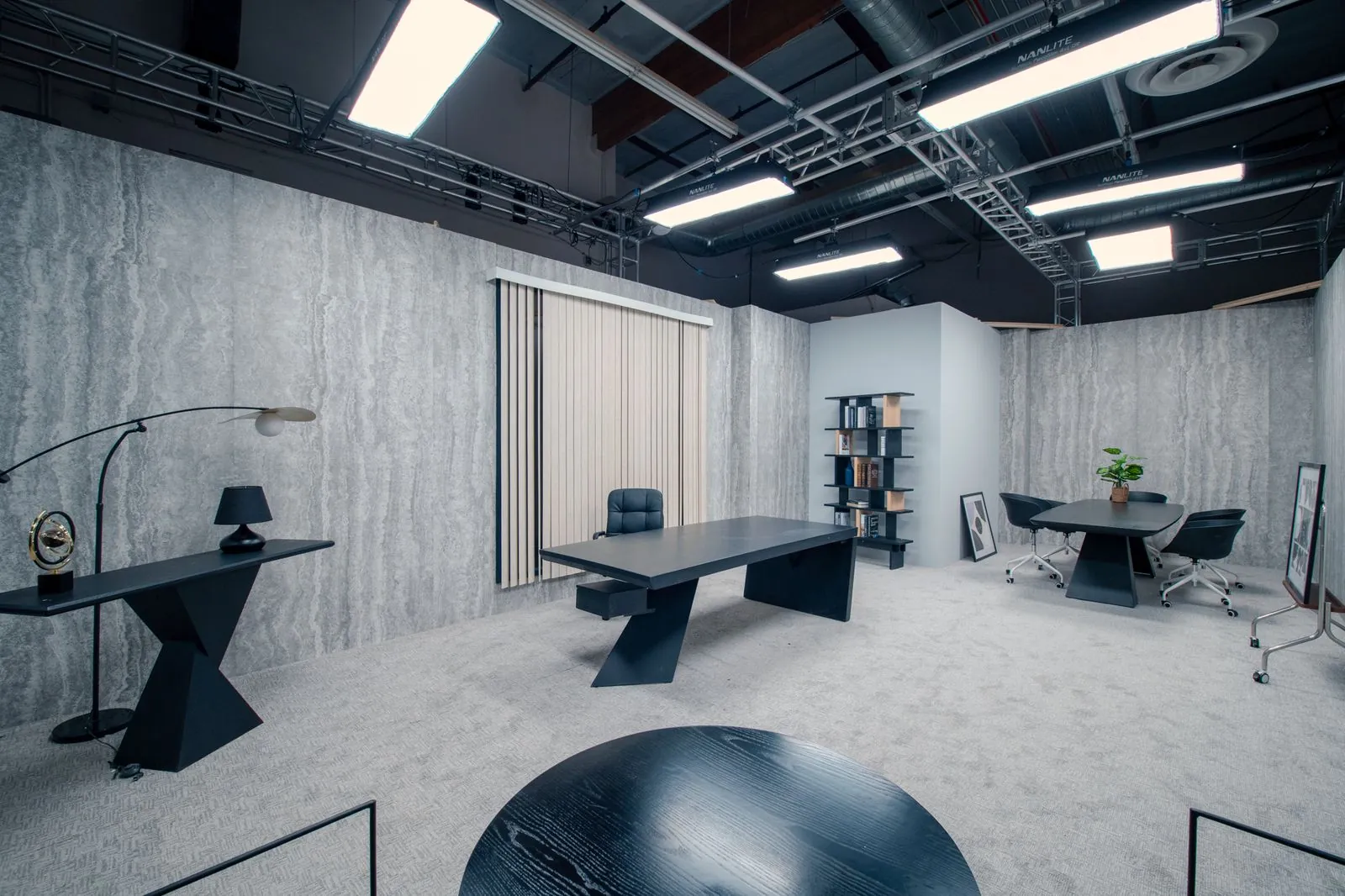 Private office with desk, console and a round meeting table beyond