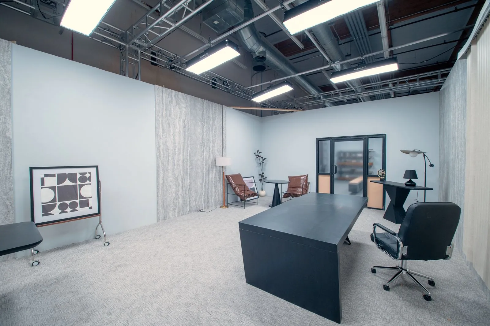 Private office with glass doors, leather lounge chairs and framed art